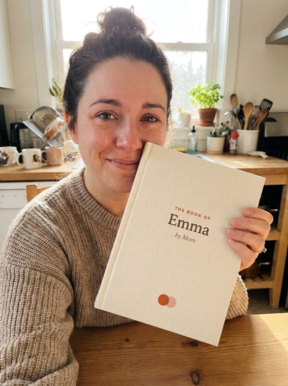 A daughter holding The Book of Emma, by Mom